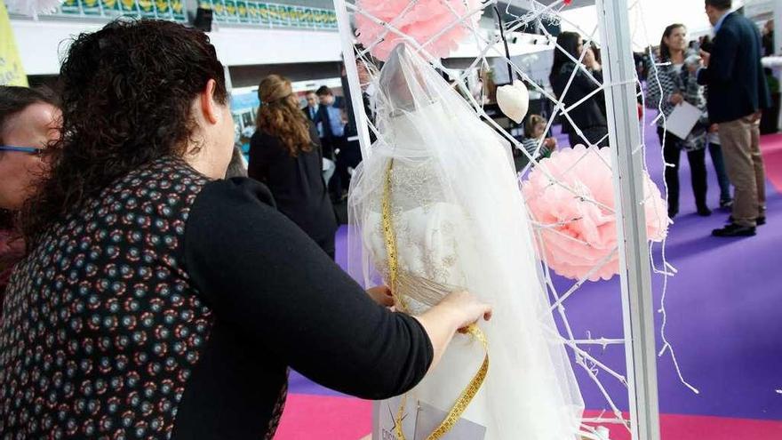 Una joven toma medidas a un traje de novia.