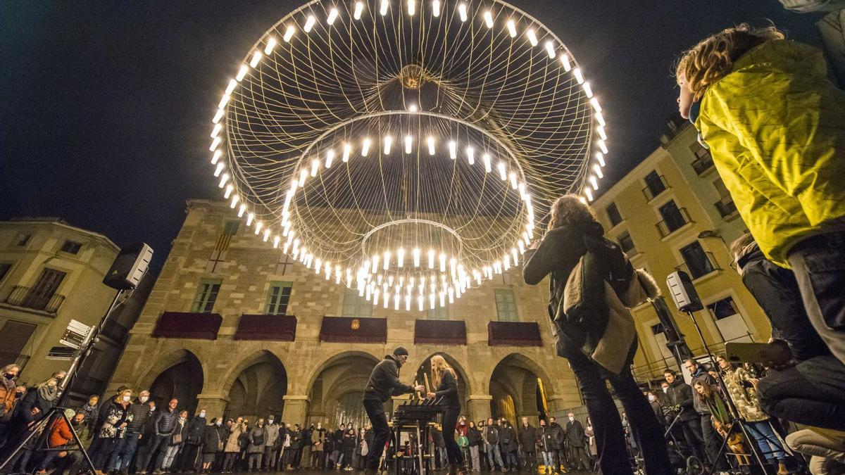 La gran làmpada feta de 150 bombetes que il·lumina tota la plaça major i que acull les actuacions d’enguany | OSCAR BAYONA