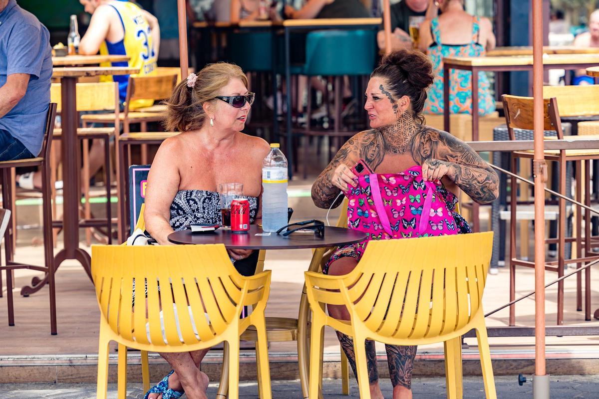 Dos turistas con bebidas en la mesa en Benidorm.