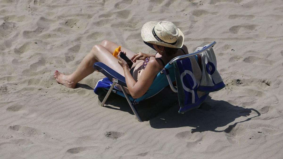 Una dona consultan el mòbil a la platja | IRMA COLLIN