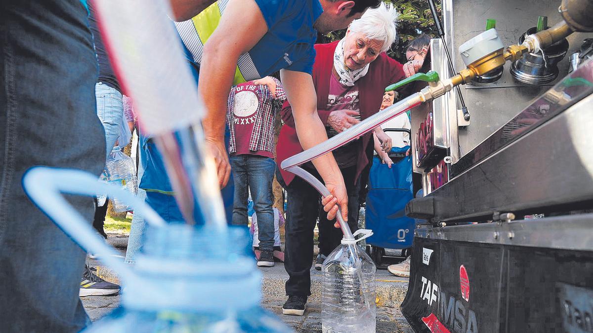 Vecinos llenan garrafas de agua de un camión cisterna, en una imagen reciente.