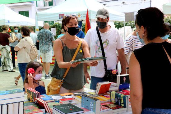 Una família comprant un conte en una parada de llibres de Sitges.