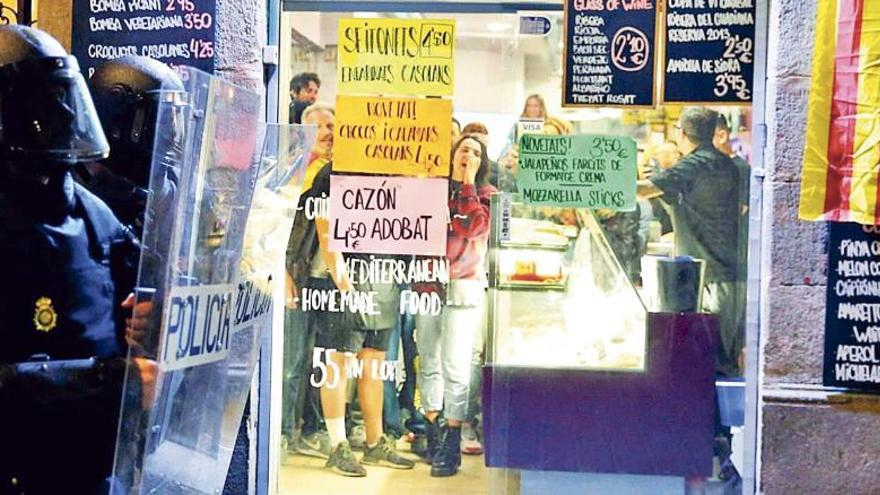 Un grupo de independentistas grita a los policías desde el interior de un ultramarinos de Barcelona.