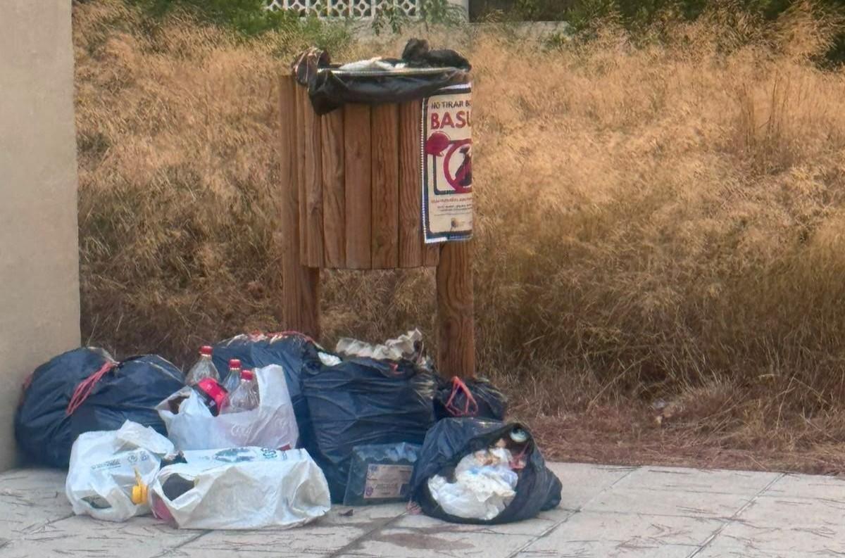Bolsas de basuras tiradas junto a una papelera