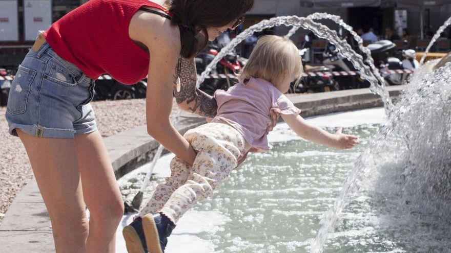 Una niña se moja las manos en una fuente para refrescarse del calor en Santa Cruz de Tenerife.