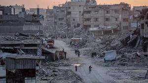 Palestinos caminando entre edificios destruidos por los ataques de Israel contra Shujaia, en el norte de la Franja de Gaza (archivo).