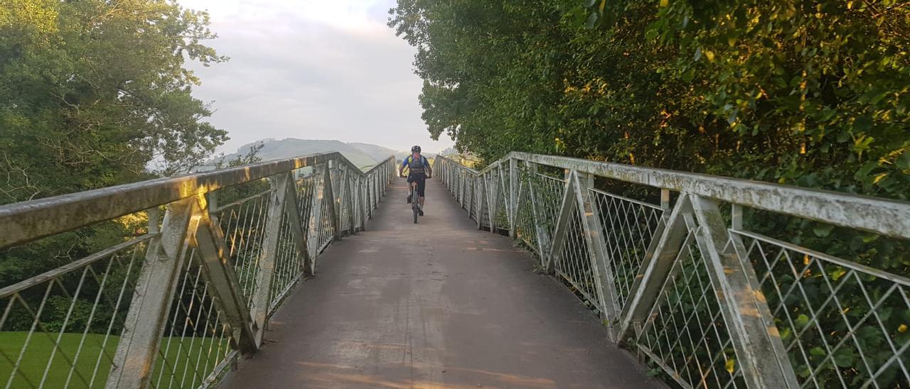 Un ciclista cruza el puente de la vía verde de La Camocha en Gijón.