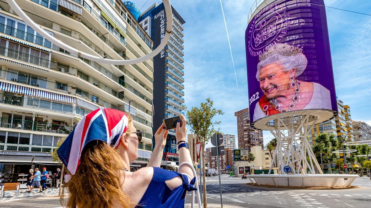 Una británica toma una foto del tecnohito de Benidorm, con una imagen de Isabel II de Inglaterra.