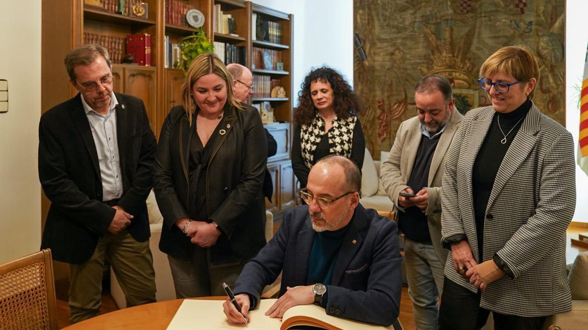 El conseller de Drets Socials, Carles Campuzano, signa el llibre d'honor en una visita a l'Ajuntament de Figueres.