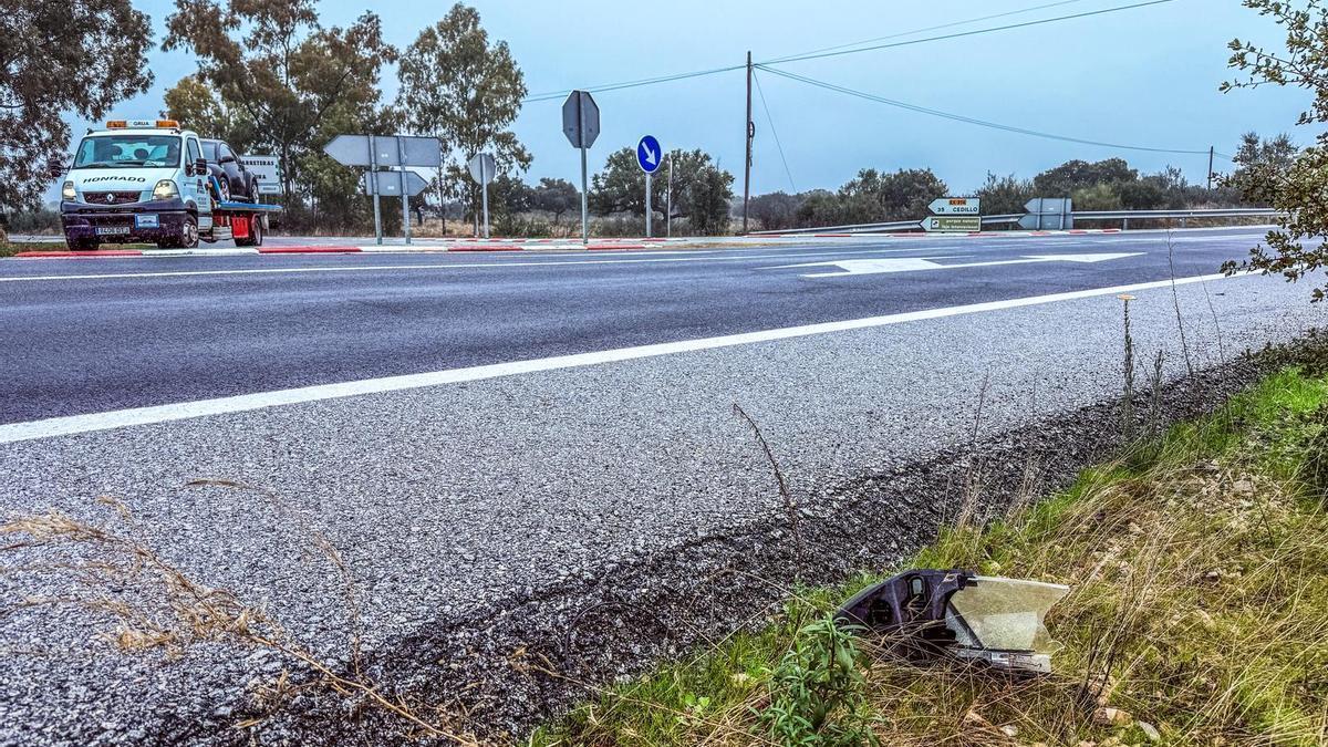 Una grúa transporta un coche siniestrado en una carretera extremeña.