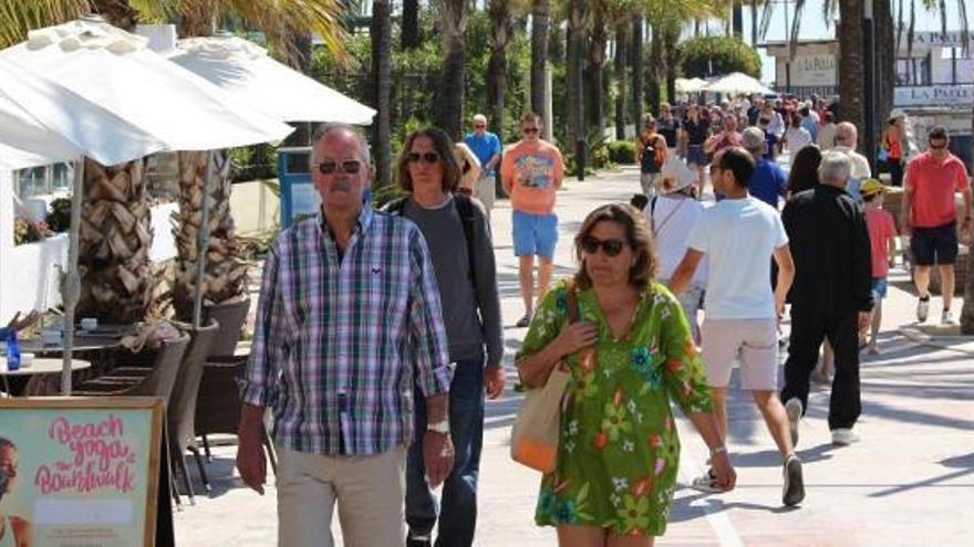 Turistas pasean por el paseo marítimo de Marbella.