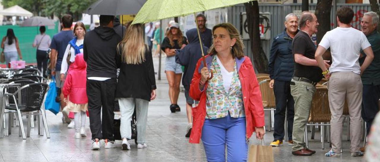 Arriba, una mujer camina por la calle Paseo con un paraguas.Abajo, el incendio de Chandrexa de Queixa y Laza. |   // IÑAKI OSORIO Y BRAIS LORENZO