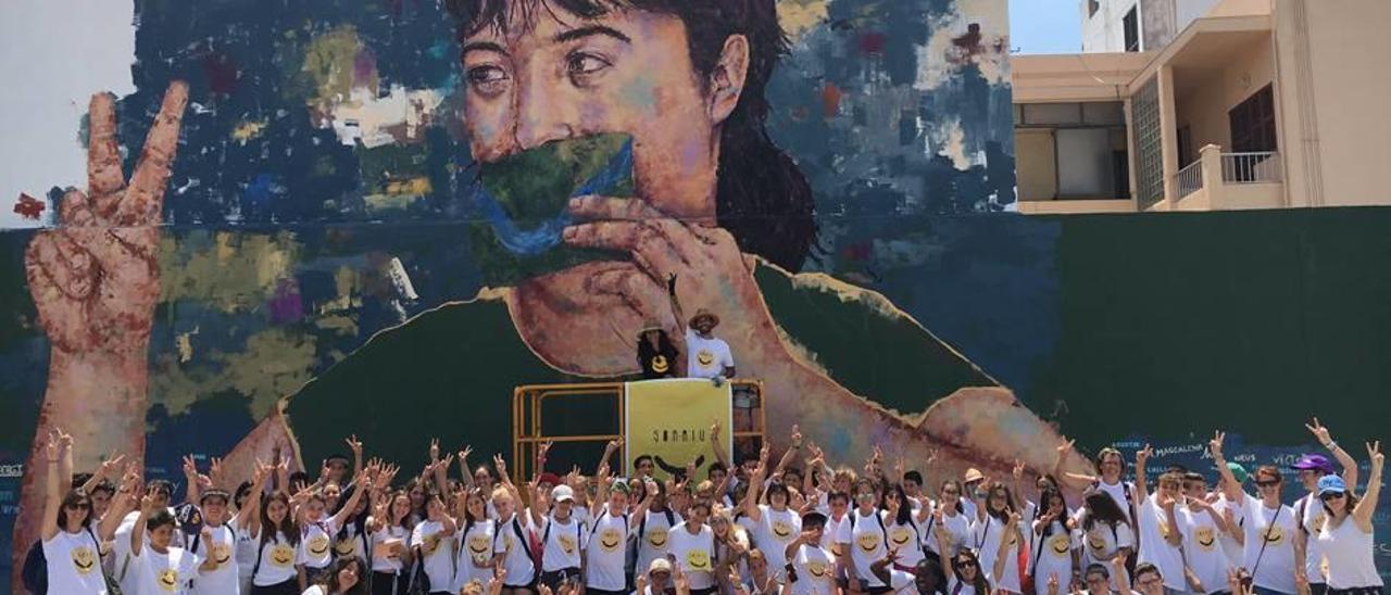 Los alumnos posan con el artista Sath frente al mural del Cap Vermell.