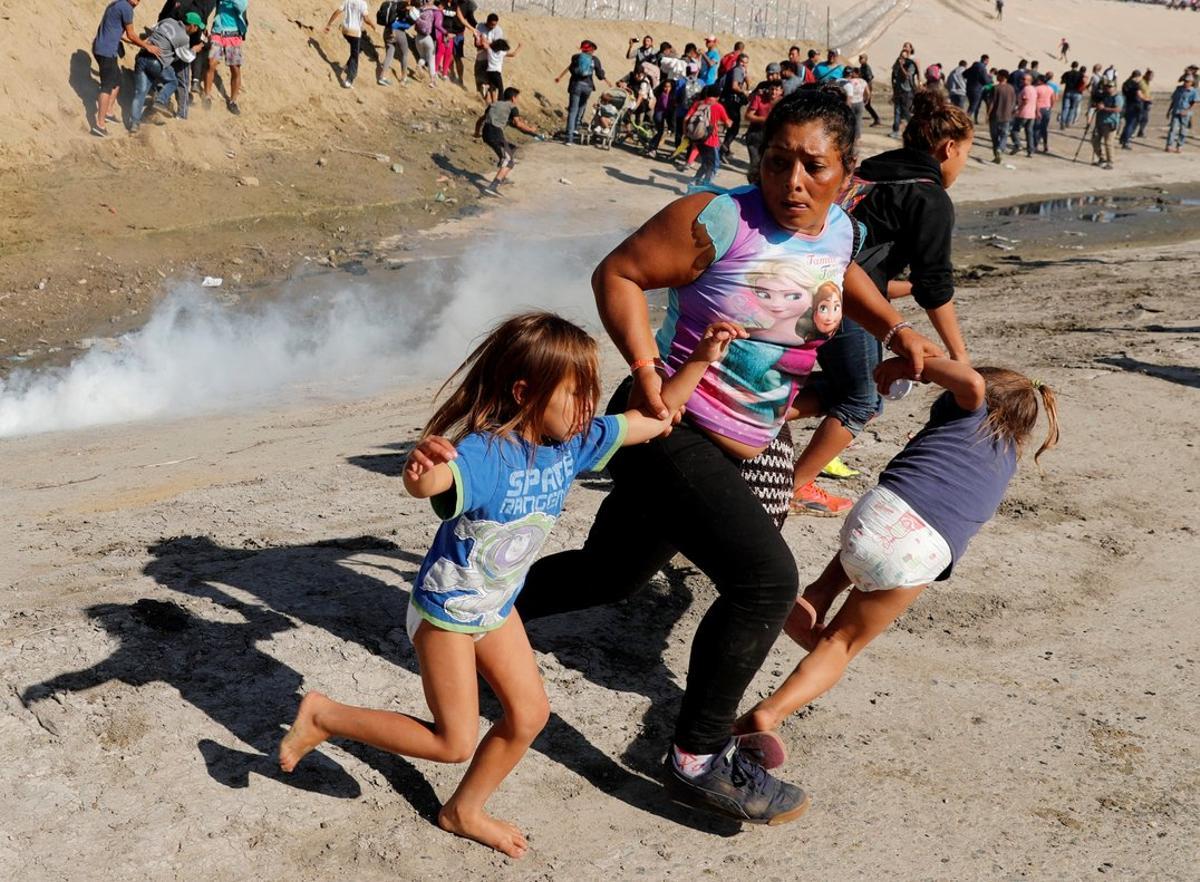 A migrant family from Honduras, part of a caravan of thousands traveling from Central America en route to the United States, runs from tear gas released by U.S. border patrol near the fence between Mexico and the United States in Tijuana, Mexico, November 25, 2018. REUTERS/Kim Kyung-Hoon