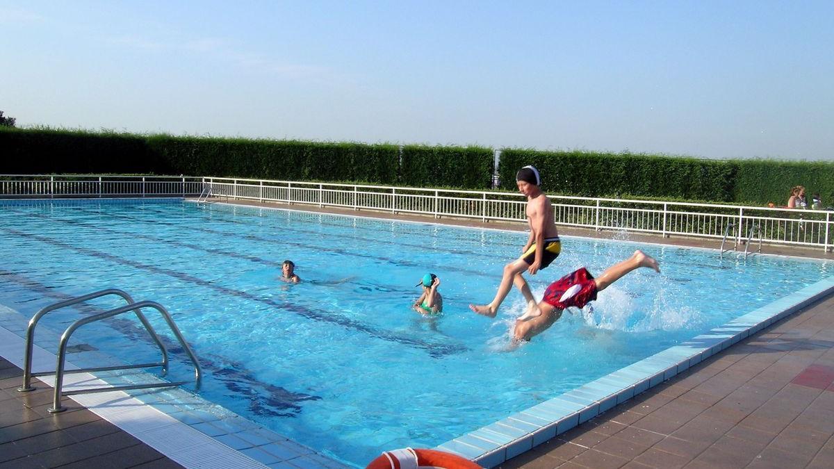 Unos chicos saltan a una piscina.