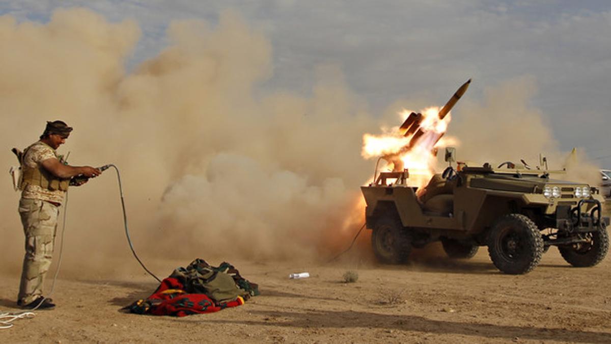 A Shi'ite fighter launches a rocket during clashes with Islamic State militants on the outskirts of al-Alam