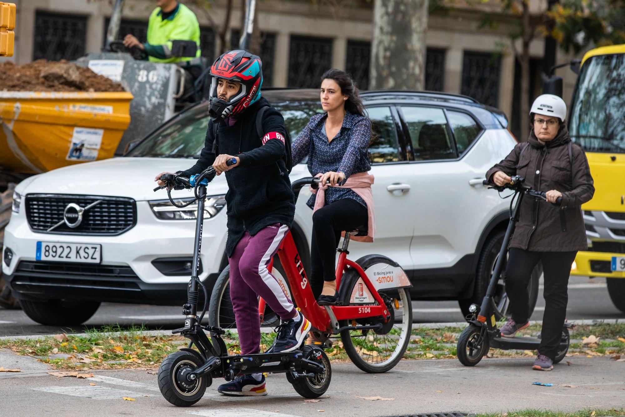 Usuario de patinete eléctrico con casco integral por las calles de Barcelona