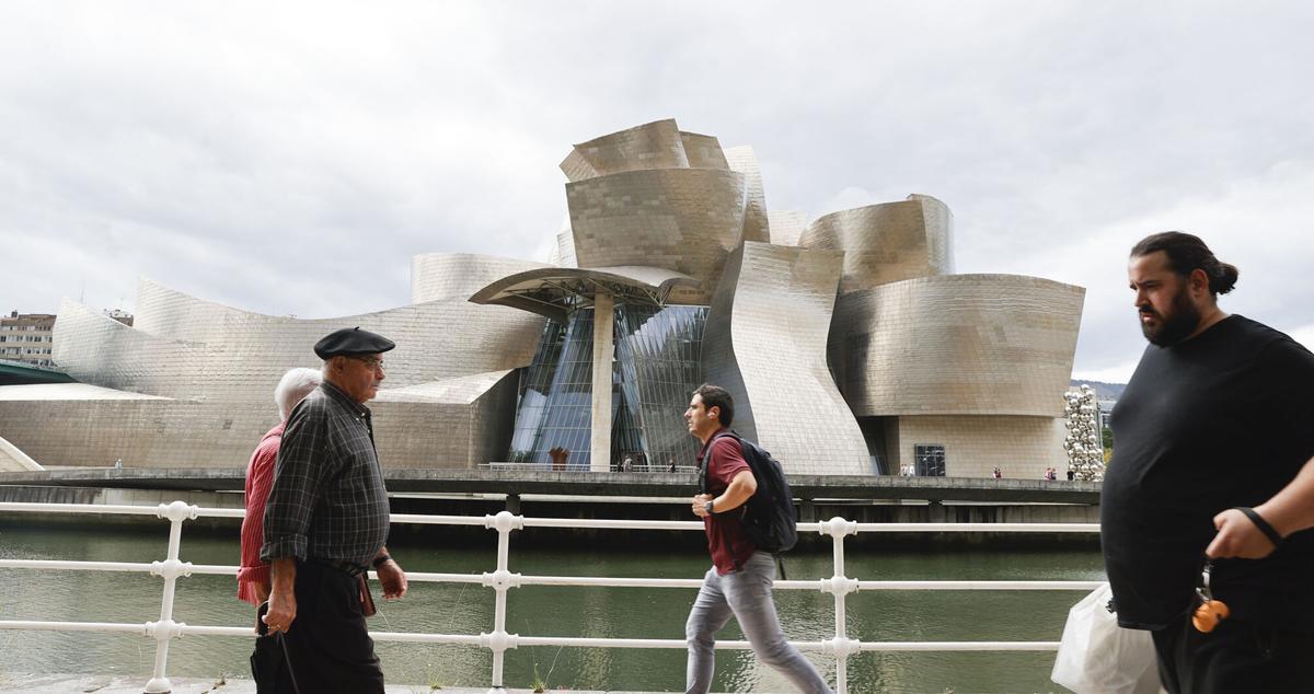 GRAFCAV1600. BILBAO, 17/10/2022.-Personas pasan ante el Guggenheim de Bilbao, obra del arquitecto Frank Gehry donde se conmemora el aniversario de la obra que creó hace 25 años. El artista canadiense se ha desplazado hasta la capital vizcaína para asistir a los actos del 25 aniversario de una de sus obras emblemáticas, inaugurada el 18 de octubre de 1997, en la que este martes será presentada la exposición "Secciones/Intersecciones. 25 Años de la Colección del Museo", que ocupa todas las salas del centro. EFE/Luis Tejido