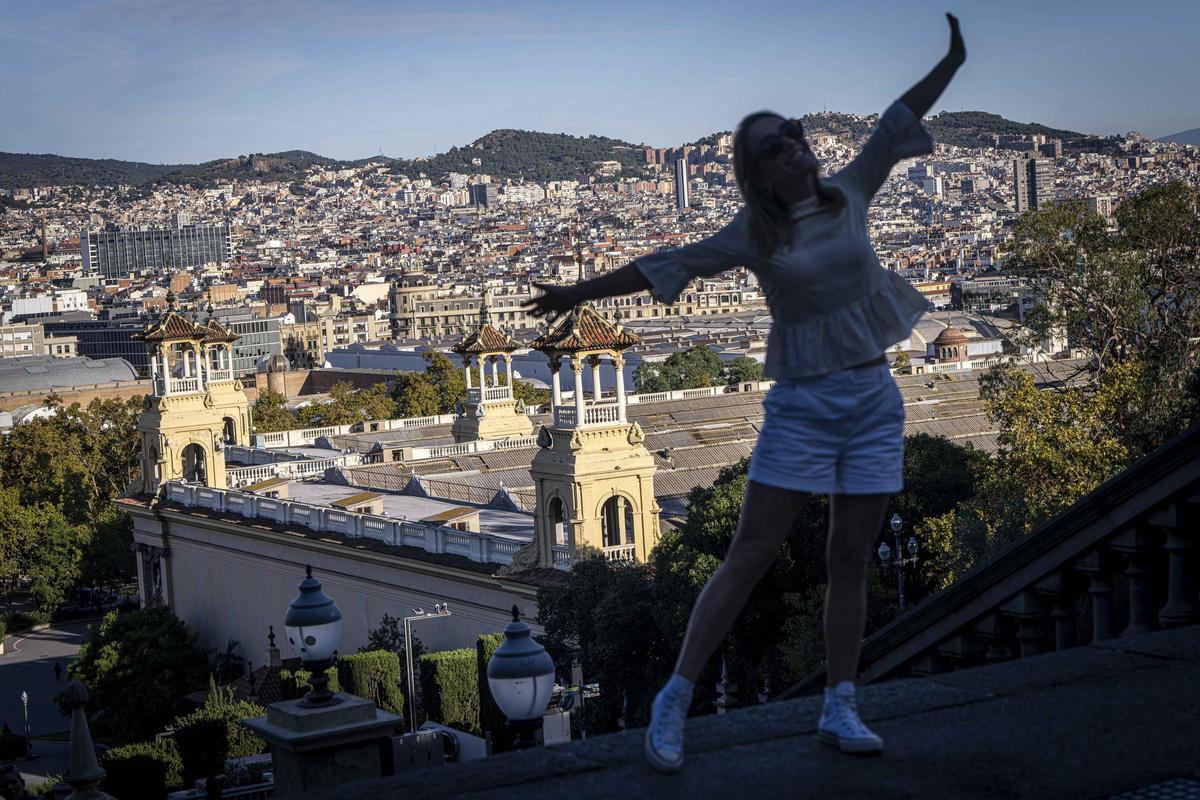 Una turista posa para una fotografía en Montjuïc, con el palacio de Alfons XIII al fondo, en la Fira de Barcelona.