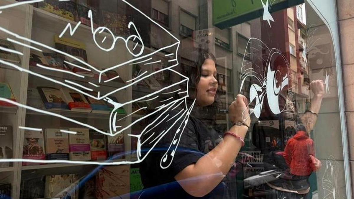 Estudiantes del IES Doña Jimena decorando el escaparate de la librería La Buena Letra.