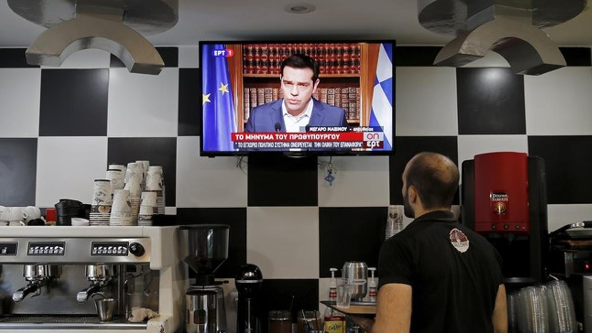 Un camarero sigue la declaración de Tsipras a través de la televisión, este miércoles en Atenas (Grecia).