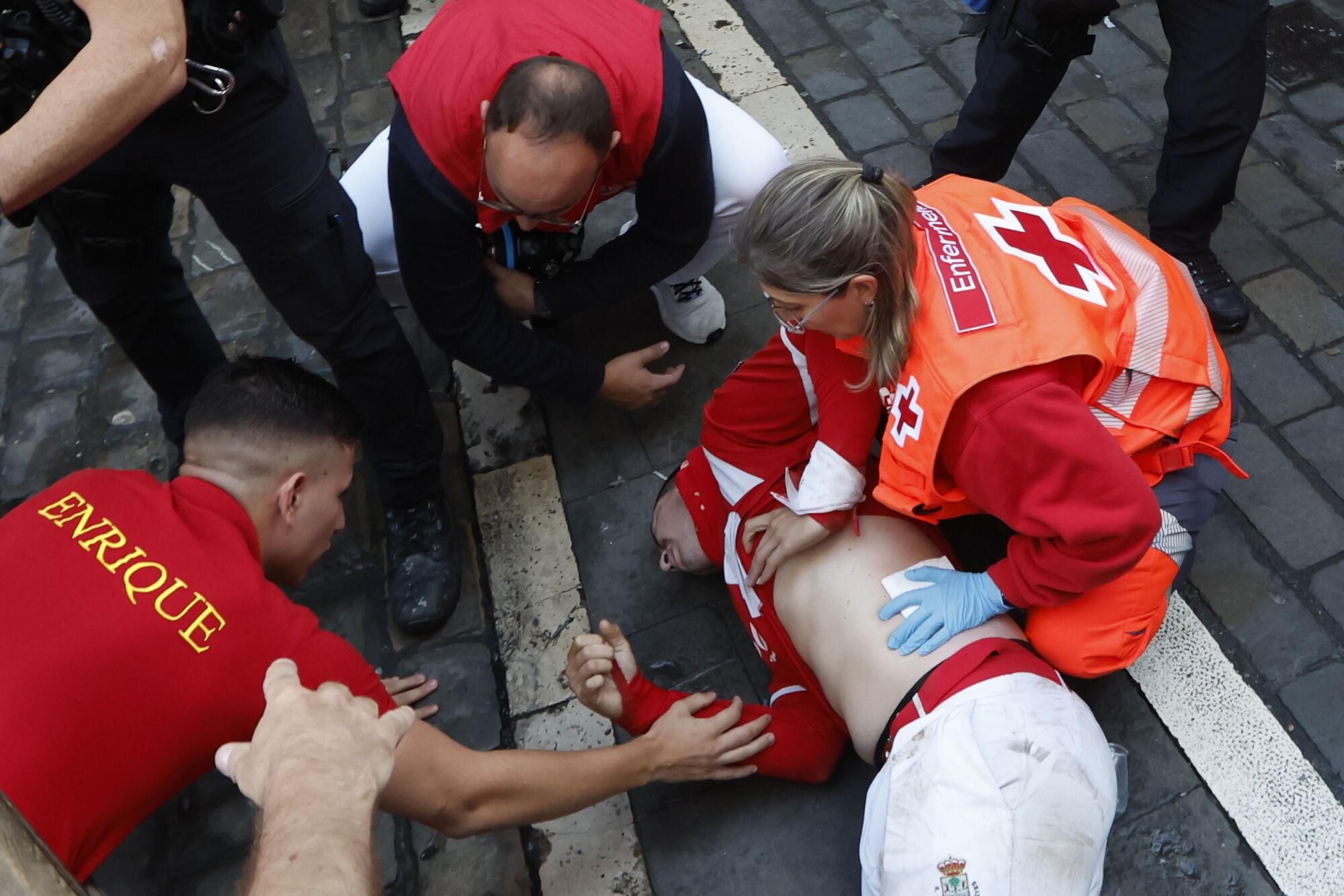 PAMPLONA, 13/07/2025.- Los servicios de emergencia atienden a uno de los mozos tras el séptimo encierro de los Sanfermines 2025 este domingo en Pamplona. EFE/Jesús Diges