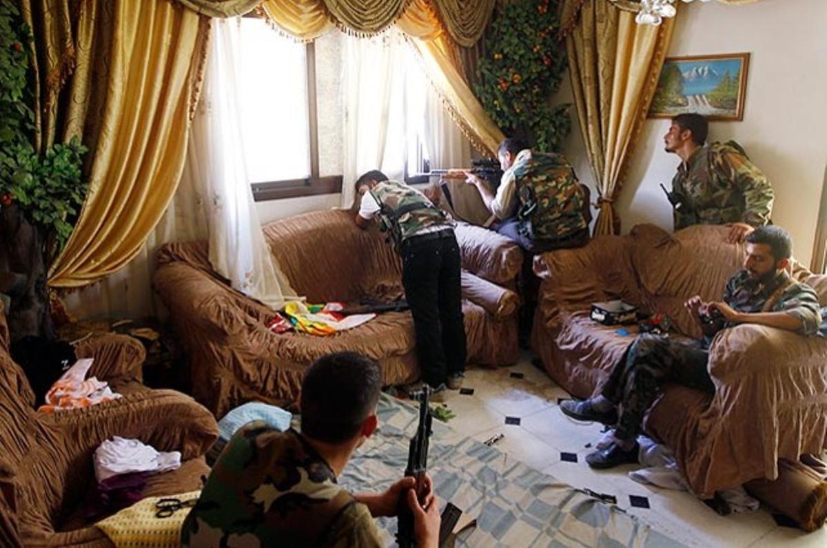 Un militar sirià dispara el seu rifle des de l’interior d’una casa a Alep.