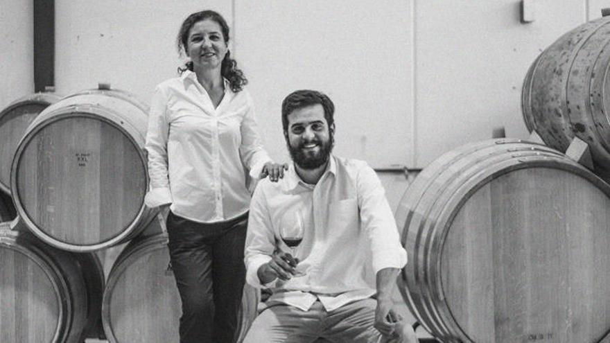 Victoria y Guillermo posan delante de unos barriles de vino de su bodega.