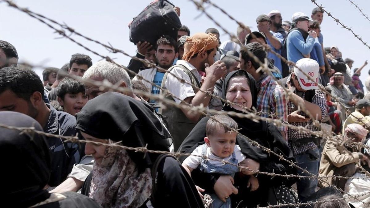 Refugiados sirios esperan cruzar desde su país la frontera que les separa de Turquía cerca de Akcakale  en la provincia de Sanliurfa.
