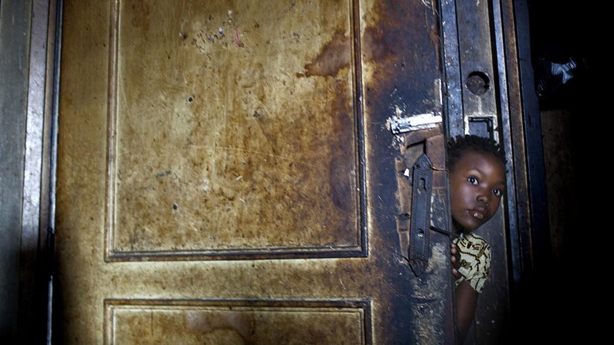 Una niña residente en el Grande Hotel de Mozambique se asoma por una puerta de ese edificio fantasma abandonado en 1963.