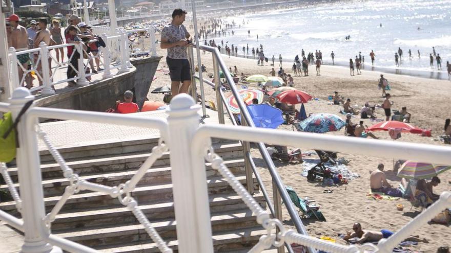 Bañistas junto a la escalera 8, donde minutos antes los socorristas rescataron a un hombre indispuesto en el agua ante una playa abarrotada. | M. Fuentes