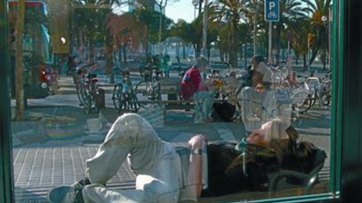 Un joven, tumbado en un banco del paseo de Joan de Borbó de Barcelona.
