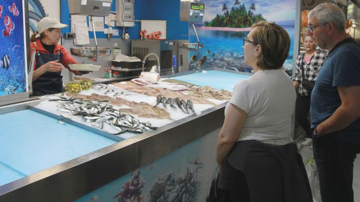 Dos clientes en una pescadería observan el género.