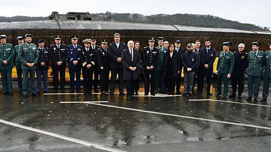 El delegado del Gobierno (centro), con la delegada de la Agencia Tributaria (detrás), subdelegada del Gobierno, mandos portuguesas (izda.) y de la Guardia Civil, Policía Nacional y Aduanas con el narcosubmarino de fondo, en el muelle de Aldán.