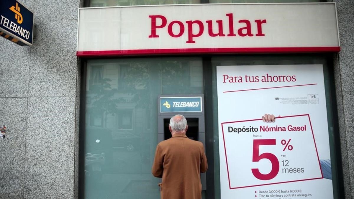 Un hombre saca dinero de un cajero del Popular en Madrid.