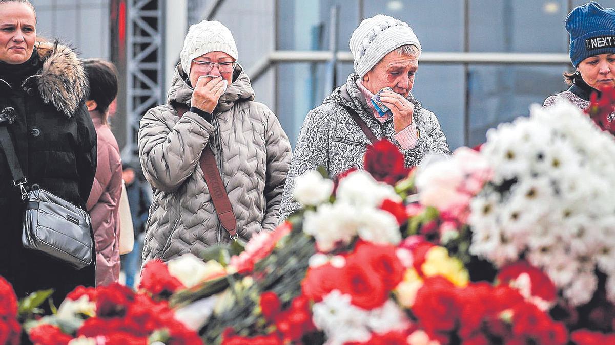 Mujeres ante flores colocadas en memoria de los fallecidos en el atentado de Moscú.