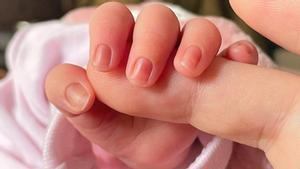 Un bebé coge el dedo de un adulto.