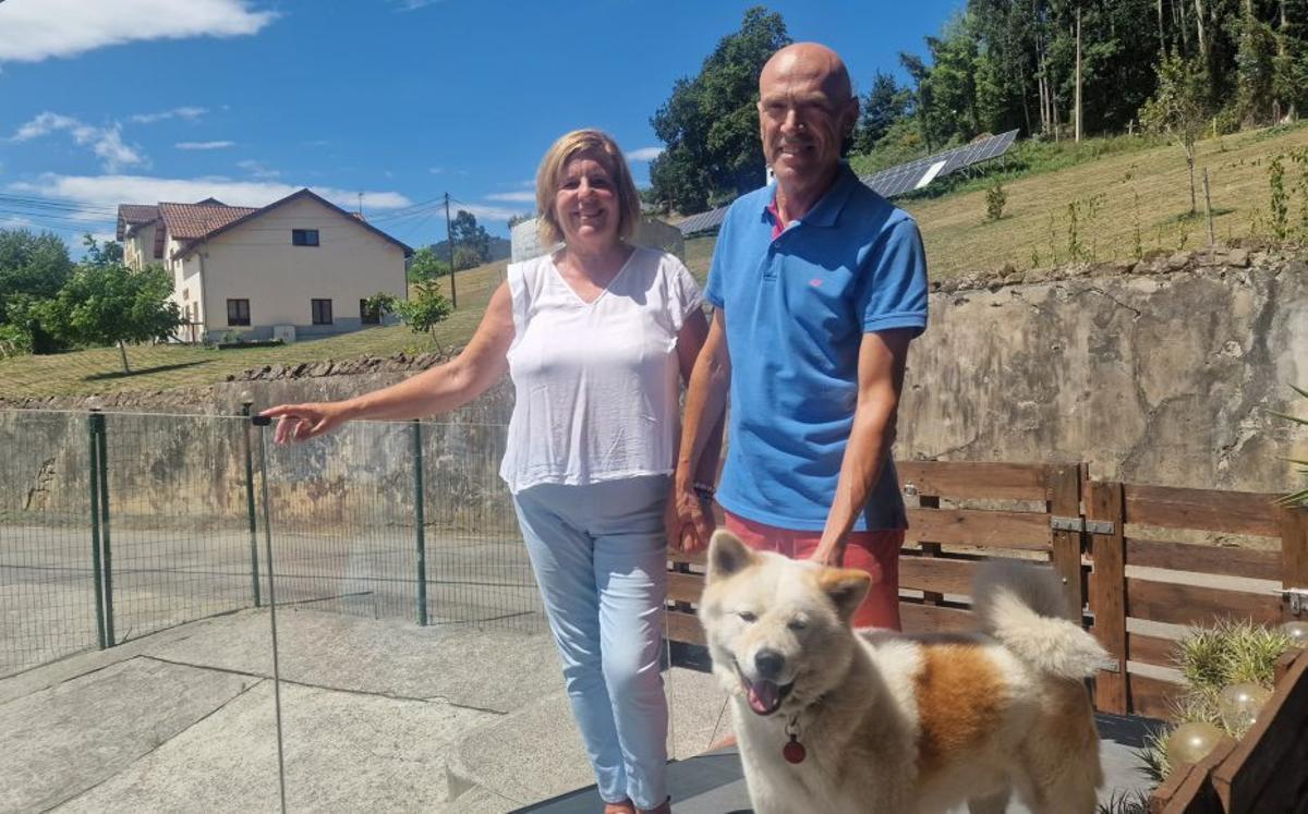 Los vecinos Javier Fernández y Gema Alonso, en su casa de Peón, con las placas solares y el centro tecnológico al fondo. |  J. A. O.