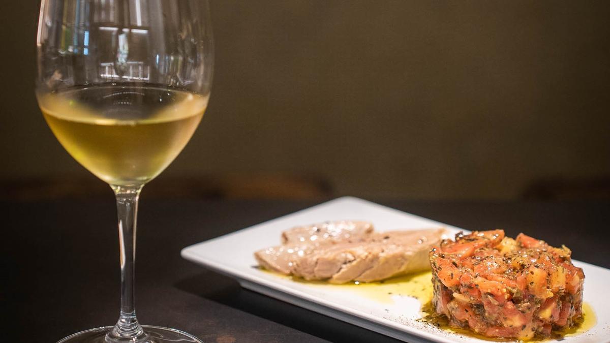 Una copa de vino blanco y un tartar de tomate con ventresca de atún de Celler Jordana.