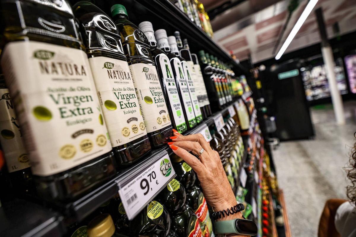 Una mujer elige entre varias botellas de aceite en un supermercado de Barcelona Una mujer elige entre varias botellas de aceite en un supermercado de Barcelona