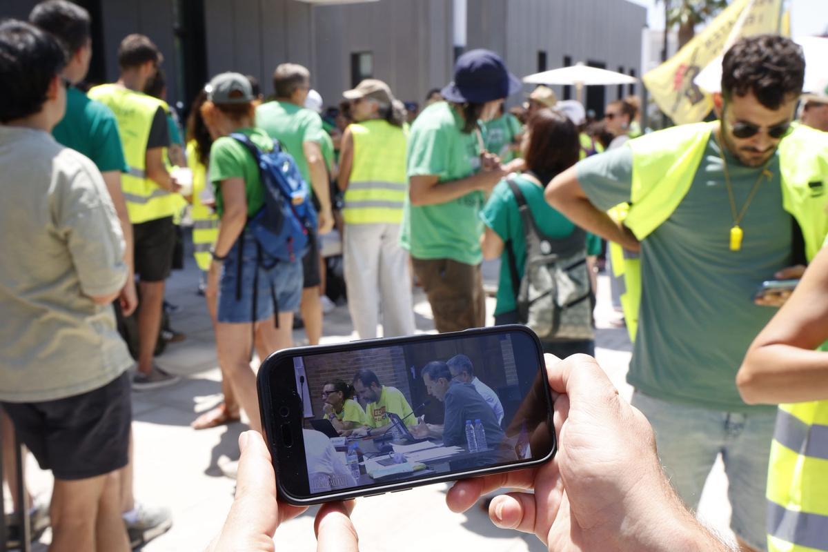 Algunos docentes en una concentración ante la Conselleria de Educación siguen la mesa de negociación en streaming