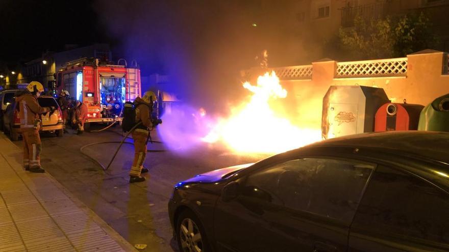 Un bombero trata de apagar las llamas originadas en el contenedor de basura, ayer.