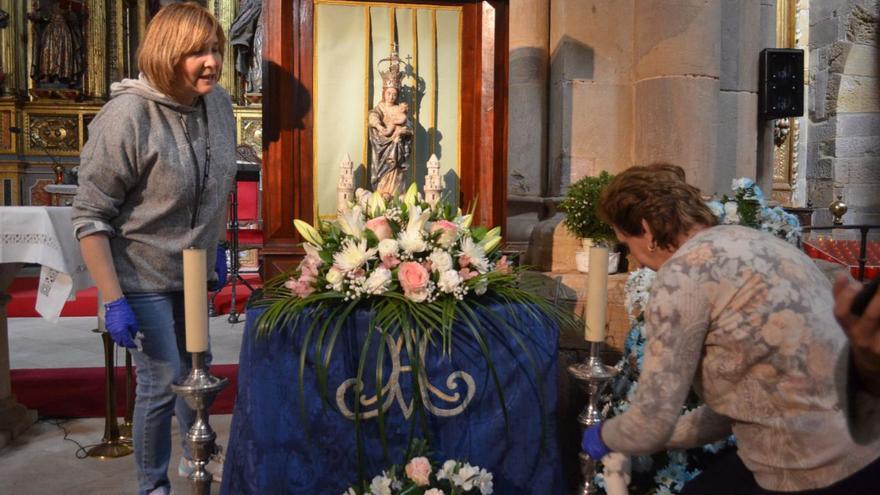 Dos mujeres preparan la imagen de la Virgen en el altar. | E. P.