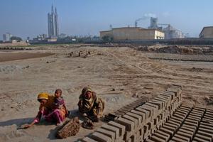 Dues dones fabriquen totxos prop d’una refineria, a Multan (Pakistan).