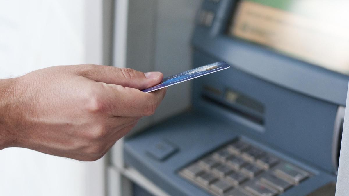 Una persona se dispone a meter una tarjeta de crédito en un cajero automático
