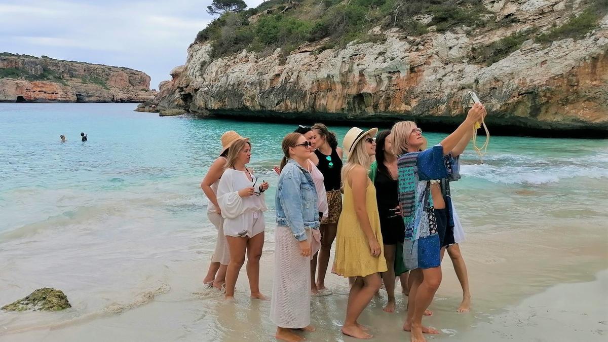 Eine Gruppe von Frauen fotografiert sich am Strand von Caló des Moro bei Santanyí.