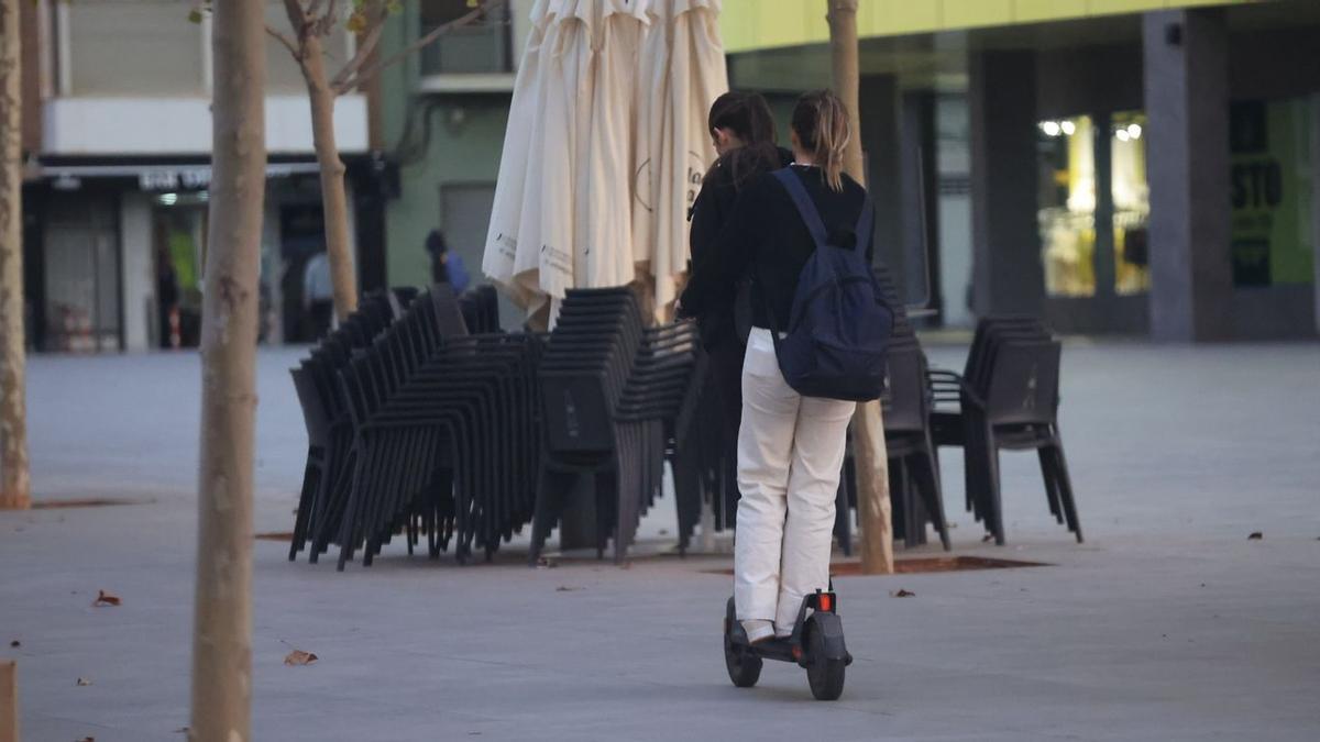 Estas jóvenes cometen dos infracciones a la vez cuando circulan por la plaza del Estadio de a Cerámica: van dos sobre un único patinete y transitan sin bajarse de él por una zona peatonal.