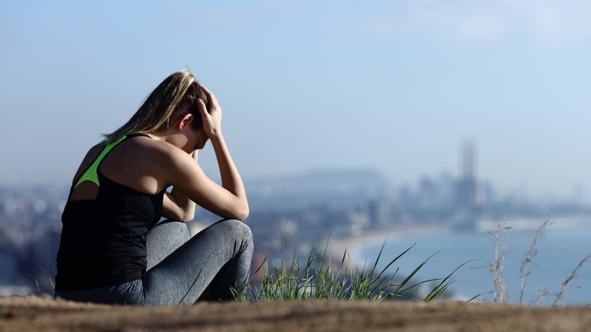 Corredora triste quejándose sentada sola en las afueras de la ciudad