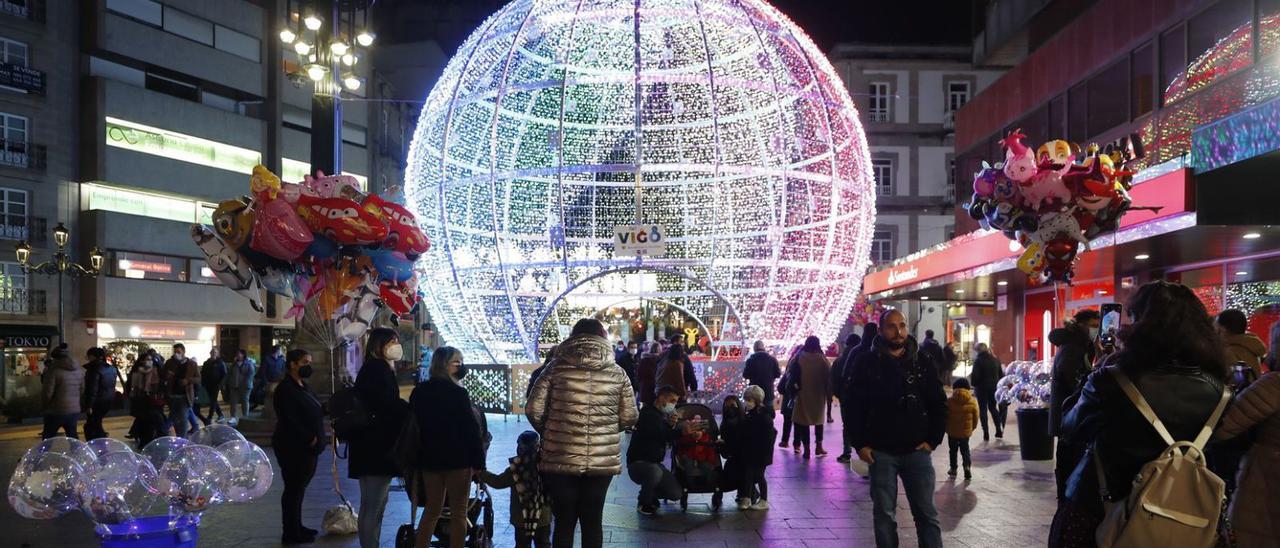 Vigueses y turistas, delante de la bola navideña de la calle Urzaiz, en Vigo.