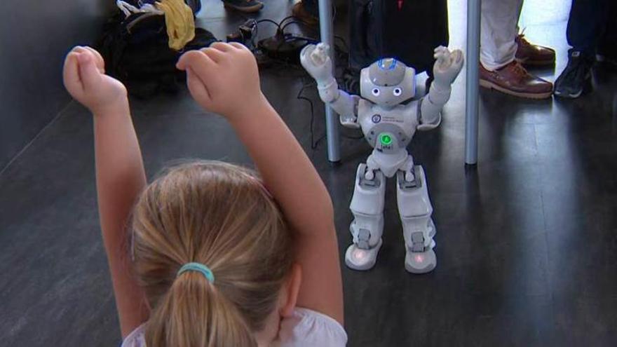 Una niña hace ejercicios de rehabilitación siguiendo las instrucciones marcadas por el robot &quot;Nao&quot;.